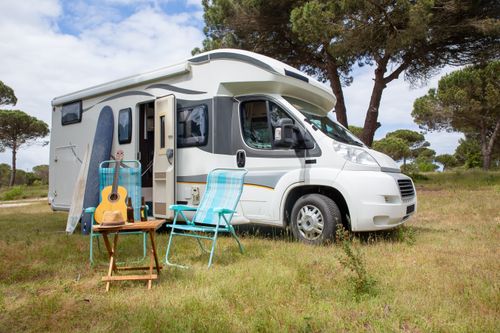 Free Explore the outdoor lifestyle with an RV, surfboards, and guitar in a serene Portuguese park. Stock Photo