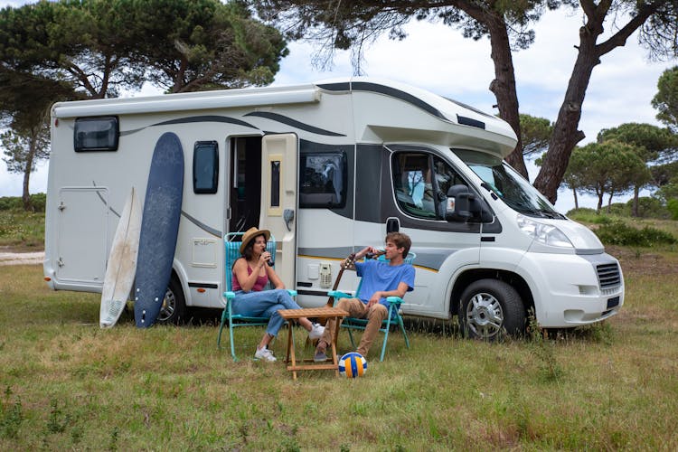 Couple Drinking Beer Bottles Beside A Van 