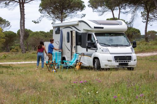 Free A couple enjoys a camping trip with their RV in a scenic grassland, surrounded by nature. Stock Photo