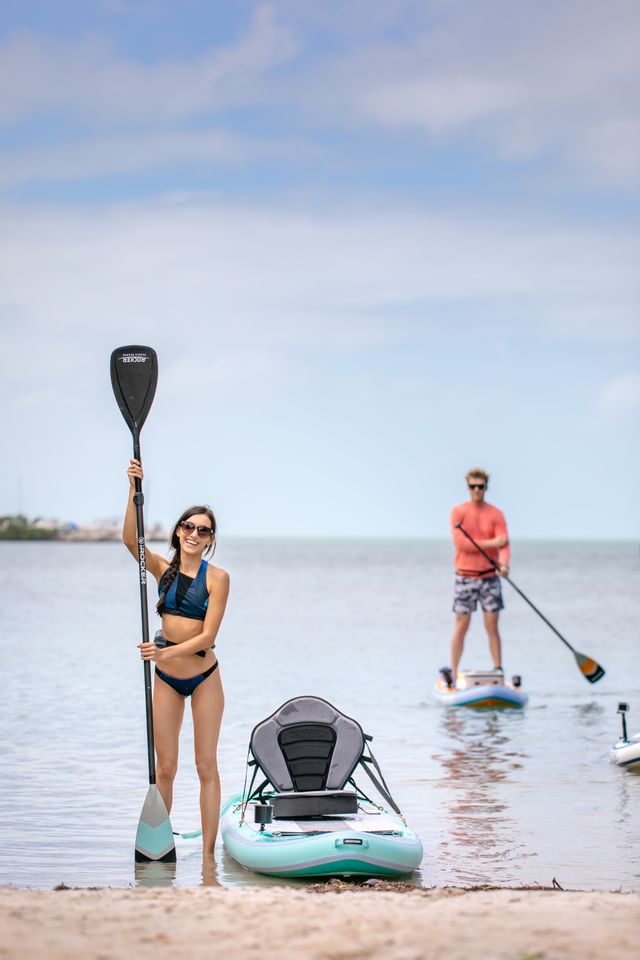 Pareja con tablas de paddle surf en un día soleado de playa