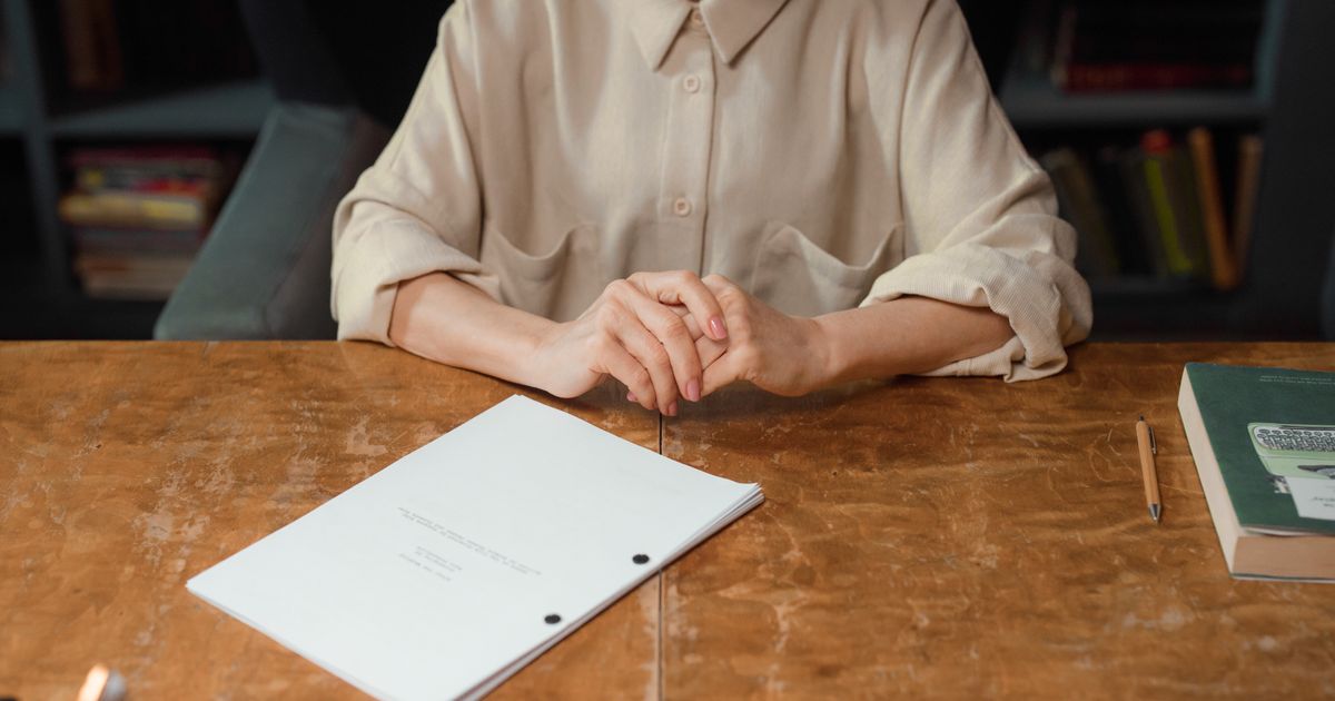 Woman sitting at wooden desk reviewing a screenplay in an office setting.