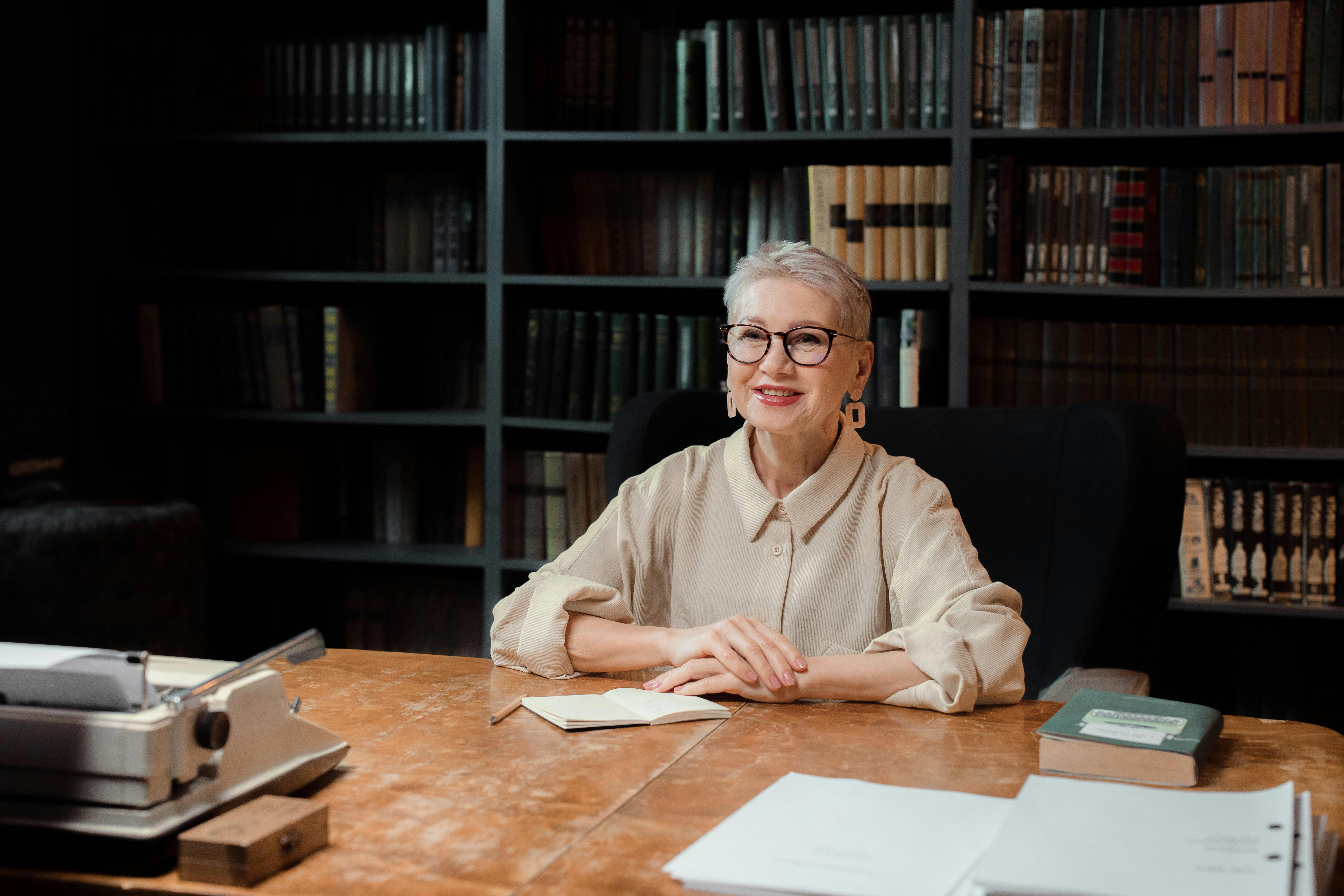 Professional Drama Professor sitting beside a Table