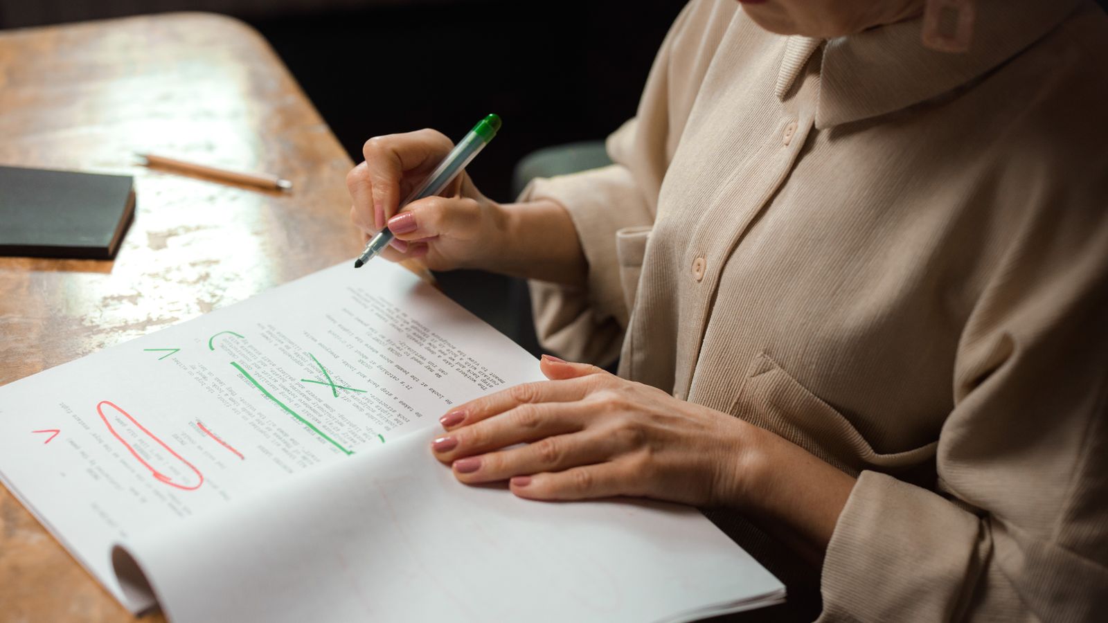 A hand marking up a printed manuscript with red and green pen