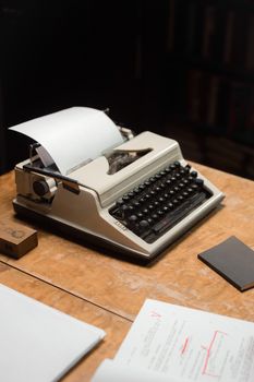 Classic typewriter on a wooden table with papers, evoking nostalgia.