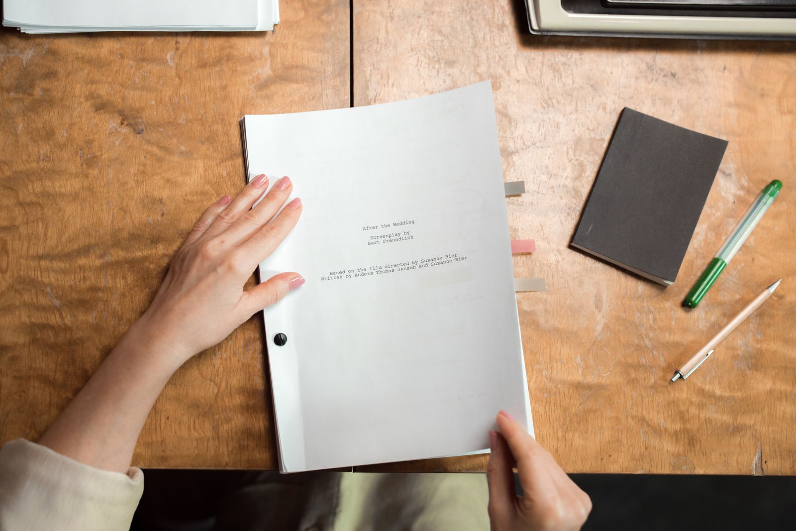 Mains organisant des documents administratifs sur un bureau avec un carnet et un stylo.