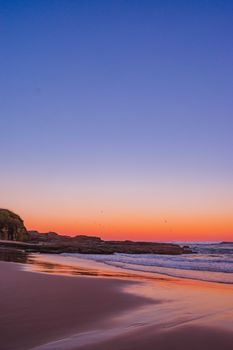 Early morning beach scene with a vibrant sunrise and calm seascape offering a serene atmosphere.