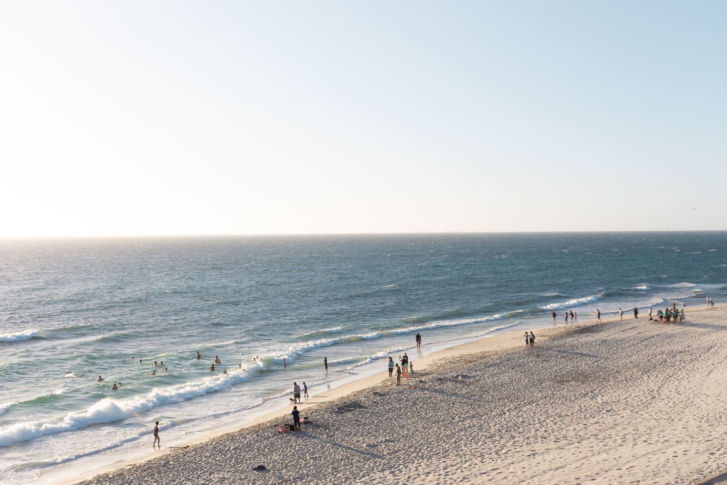 Vue aérienne tranquille de Cottesloe Beach à Perth avec des gens profitant du rivage ensoleillé et des vagues déferlantes.