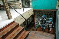 From above of anonymous man and woman in casual clothes and with backpacks walking upstairs in modern apartment