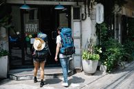 Unrecognizable couple of travellers with backpacks entering hotel