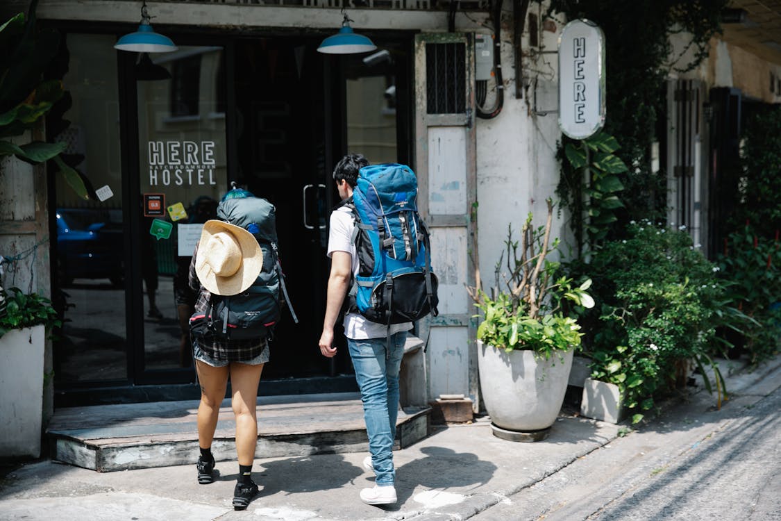 Free Unrecognizable couple of travellers with backpacks entering hotel Stock Photo