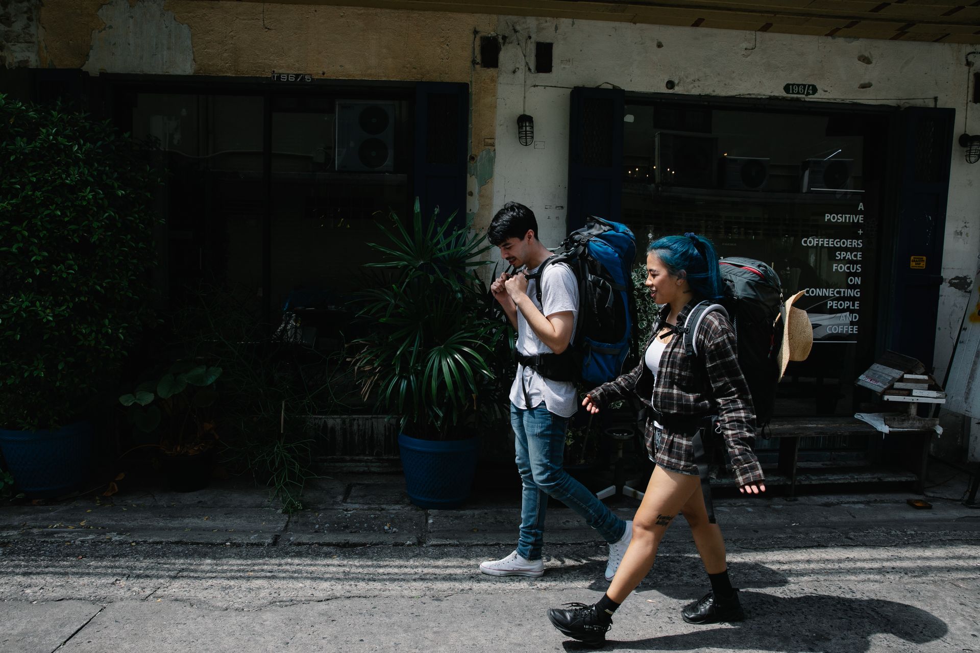 Two travellers with backpacks walking along a narrow street