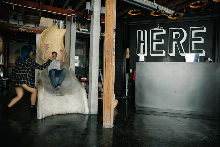 Cheerful Man Rolling Down Slide Near In Hotel Reception