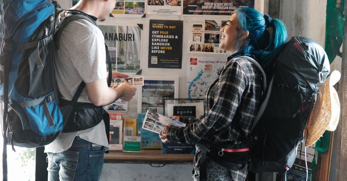 Two backpackers examining maps and brochures inside a travel information center.