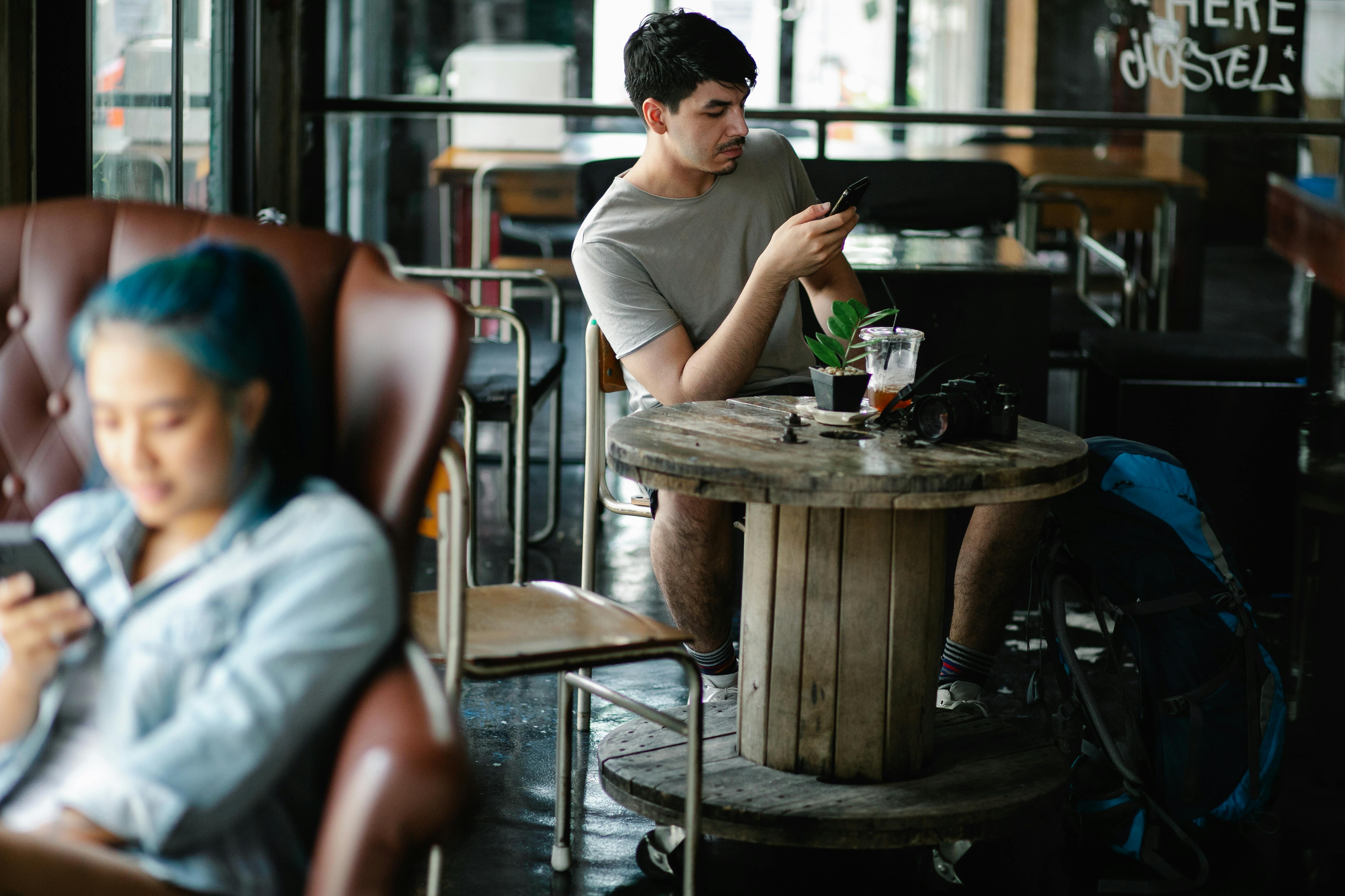 man browsing smartphone in cafe with asian woman