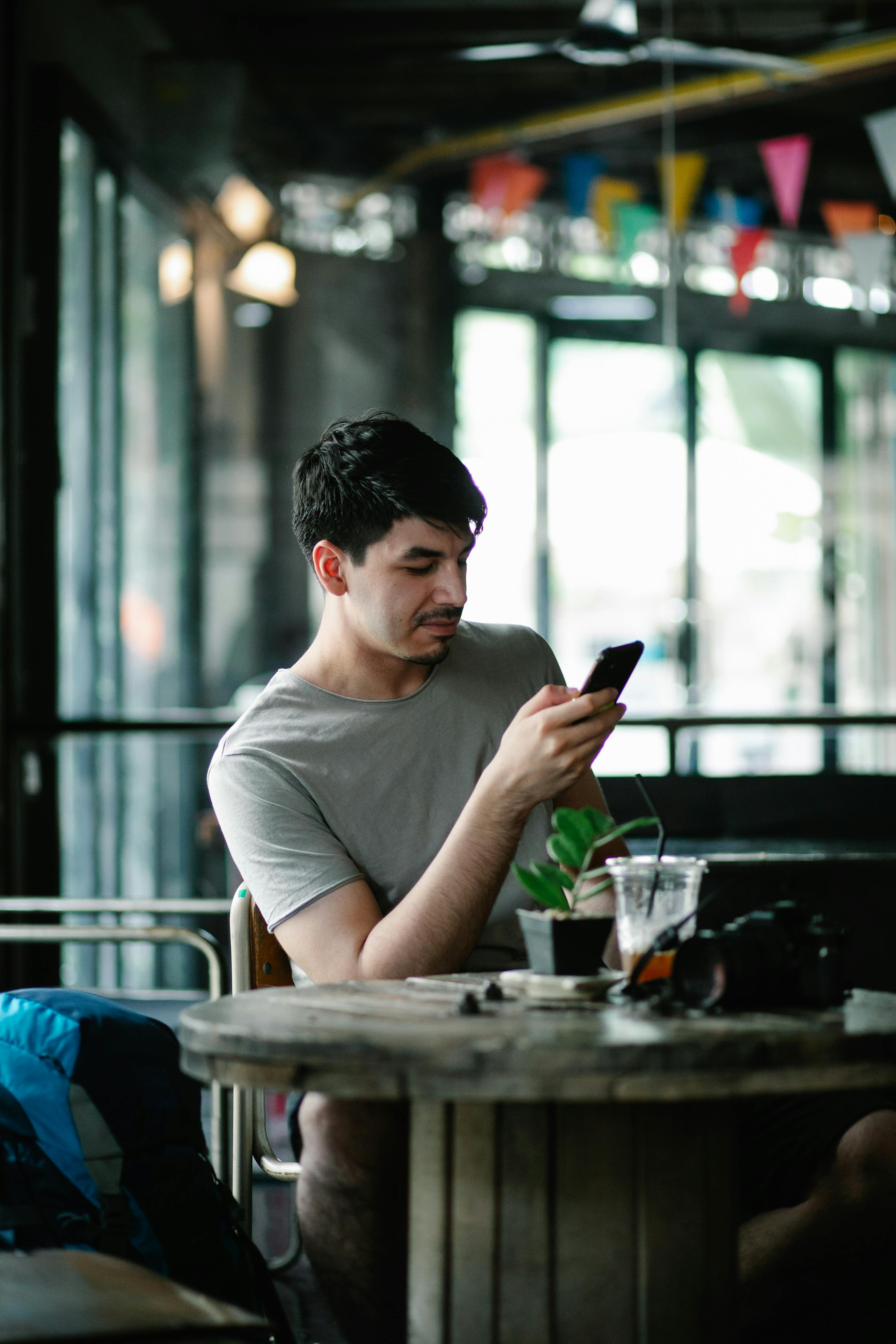 thoughtful man browsing smartphone at table