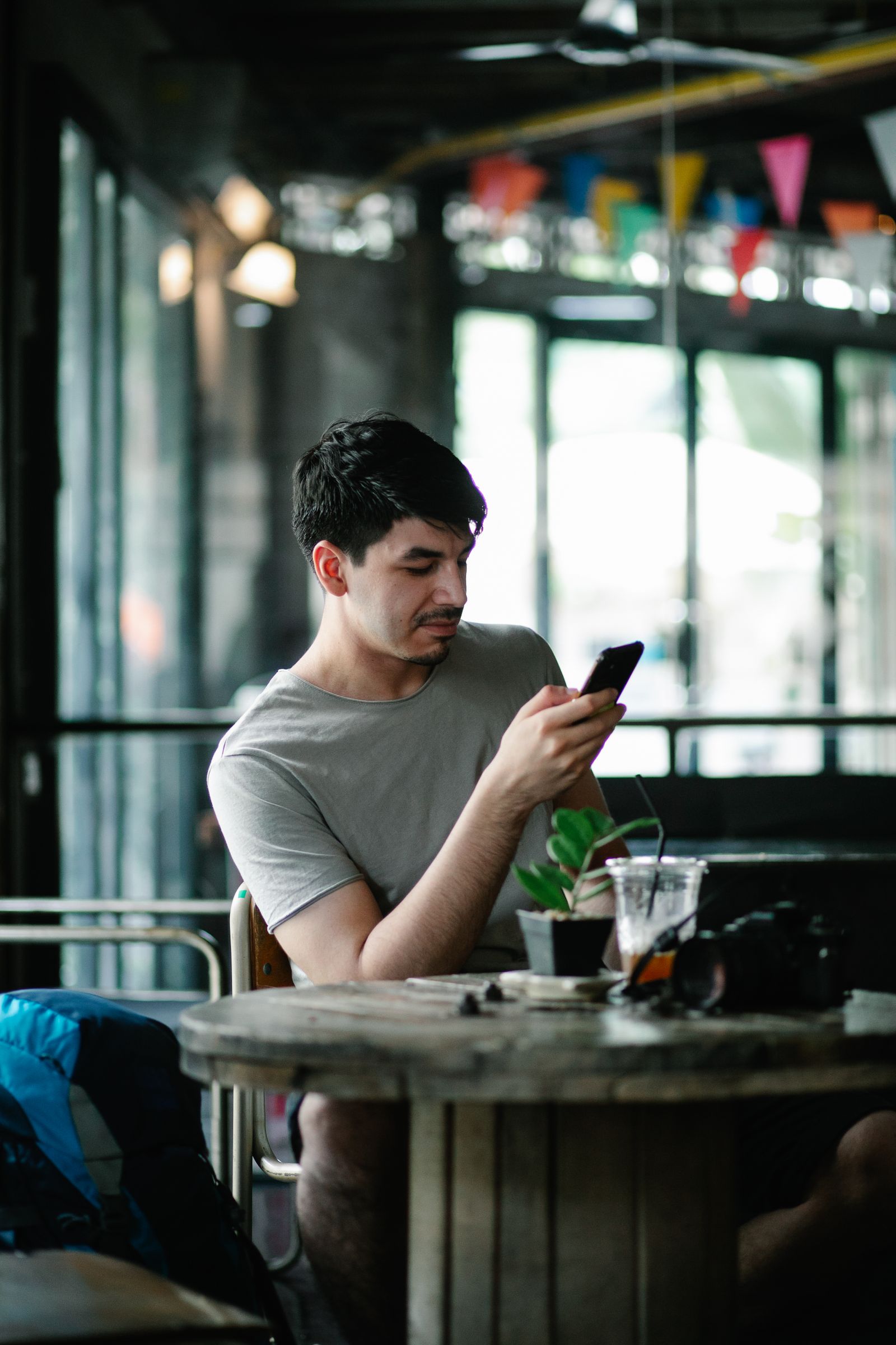 Person sitting at a café table looking at their phone
