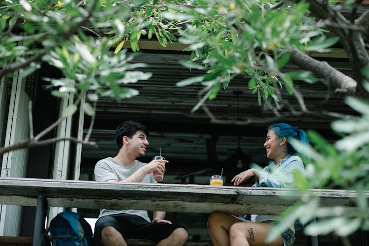 Cheerful Diverse Couple Drinking Beverages On Terrace In Countryside