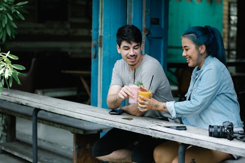 Positive multiethnic couple with refreshing drinks on terrace