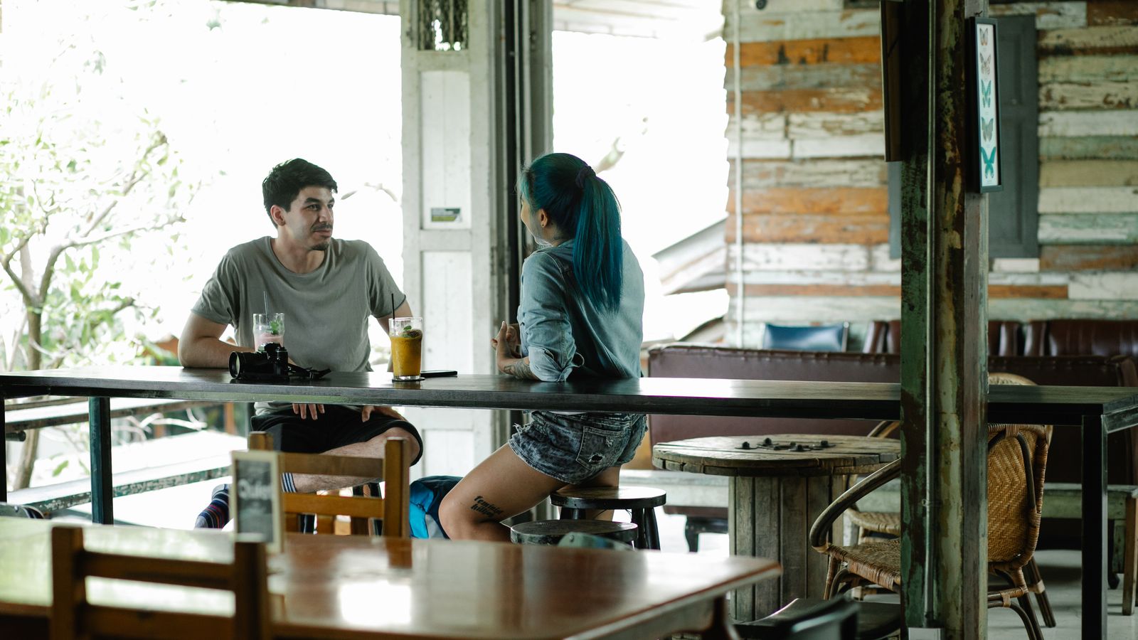 Two people talking over drinks at a wooden café table