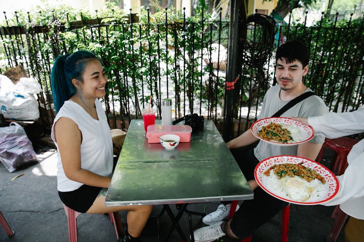 Faceless Waiter Serving Food To Diverse Couple