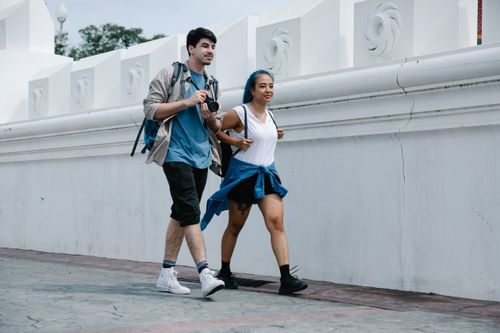 Free A couple enjoys a city walk together, capturing moments with a camera. Stock Photo