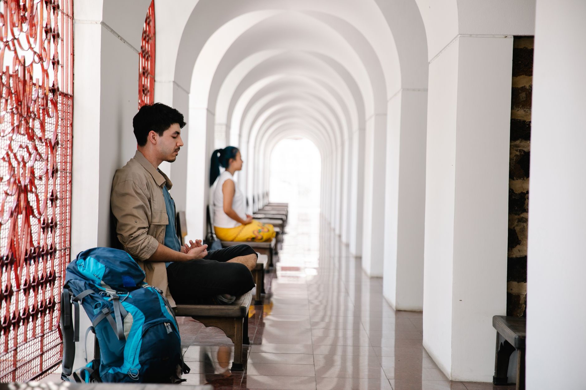 Two travelers meditate peacefully in an arched corridor, reflecting serenity and tranquility.