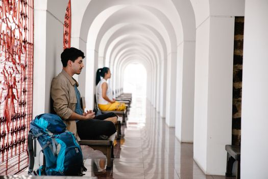 Two travelers meditate peacefully in an arched corridor, reflecting serenity and tranquility.