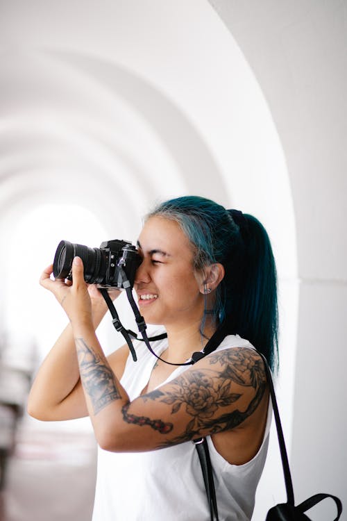 Photo of a Woman with Tattoos Using a Camera