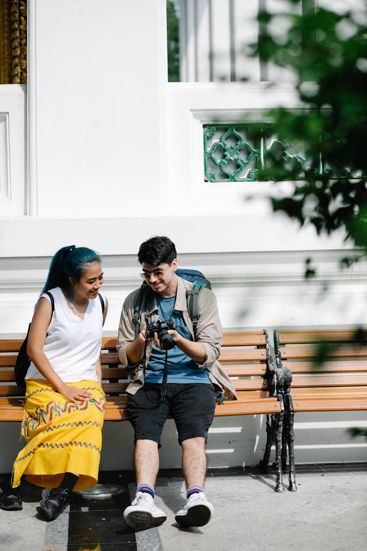 Woman And Man Looking On Bench With Camera