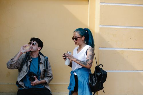 Free Casual scene of two young travelers taking a break and hydrating outdoors. Stock Photo