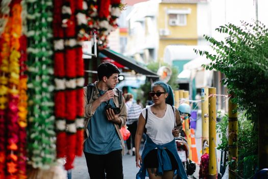 Two adults walking in a vibrant street market scene.