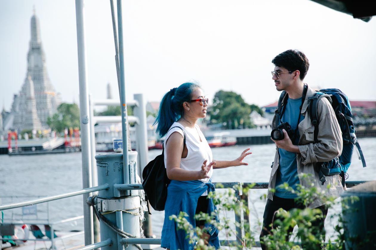 Dos mochileros charlando frente a Wat Arun en Bangkok — por qué viajar a Tailandia