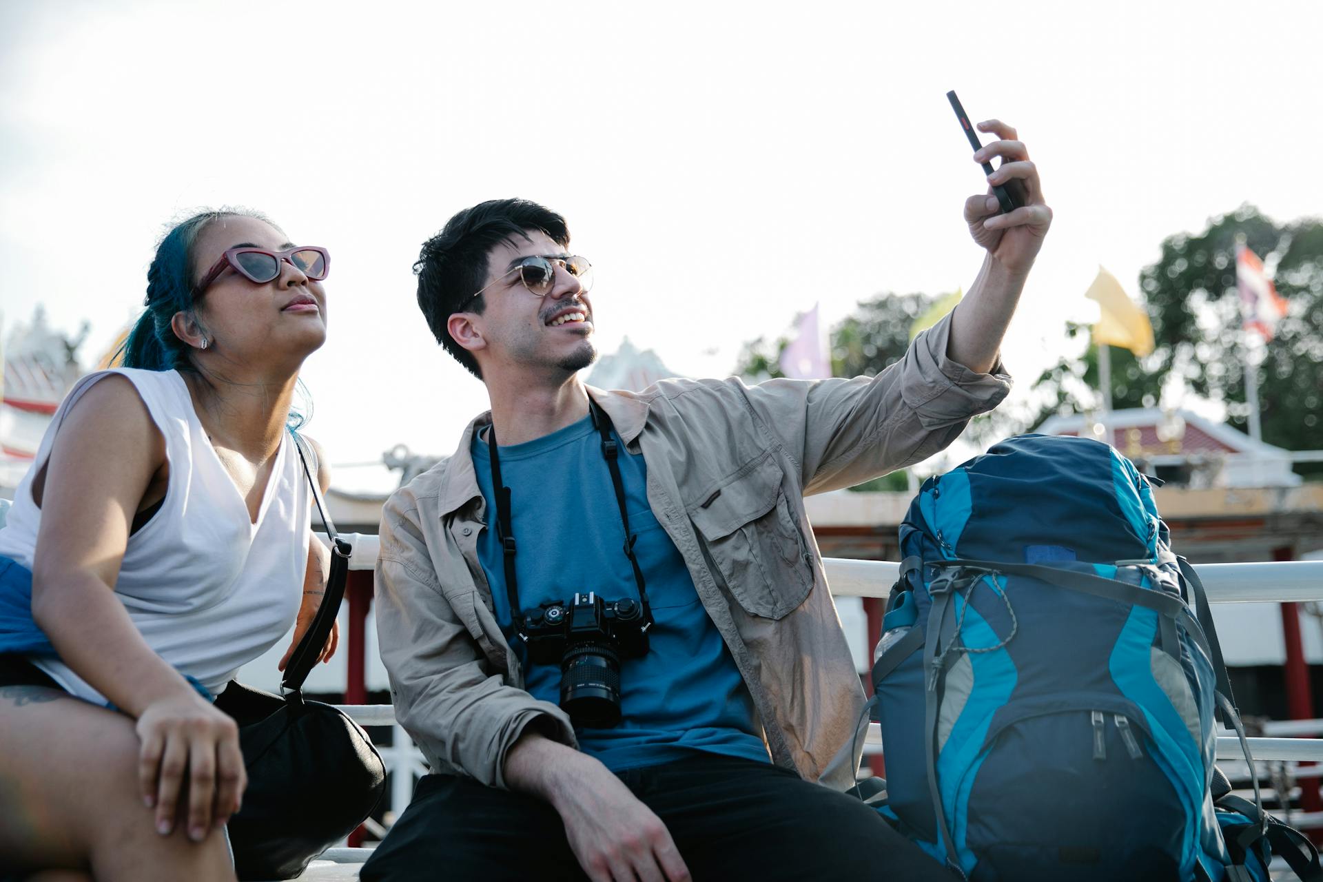 Happy tourists taking selfies on a sunny day with travel gear, capturing memories.