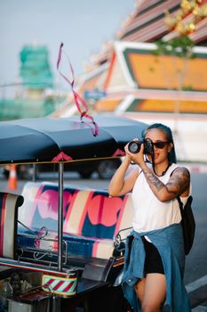 Woman with camera explores vibrant city streets in summer, capturing local life.