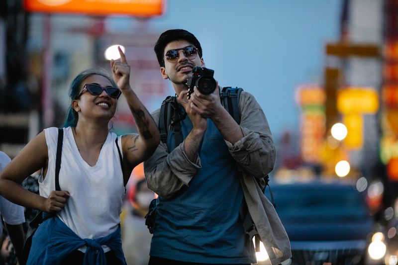 Happy couple enjoying a city adventure, capturing moments with a camera.