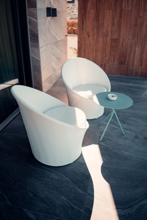 Free Stylish white chairs and table on an outdoor patio in sunlight. Stock Photo