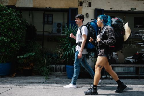 Free Two young adults walking on a city street with large backpacks, ready for adventure. Stock Photo