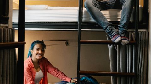 Two young travelers enjoying their hostel stay with bunk beds and backpacks.