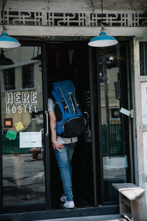 Free Man in Blue Denim Jeans Carrying a Backpack Going Inside a Building Stock Photo