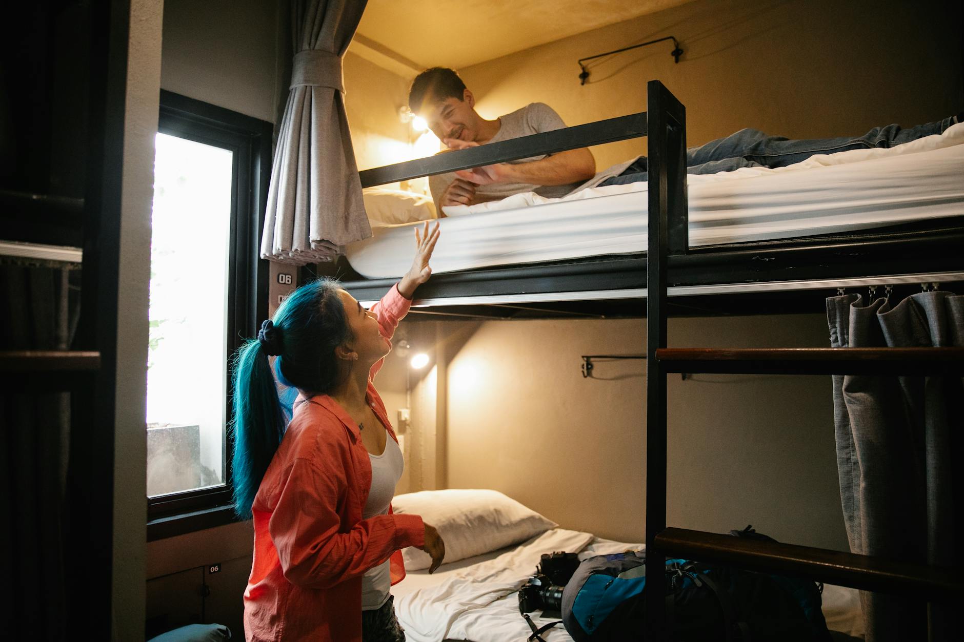 Budget Travel Bonanza: How To See The World On A Shoestring 1 young couple enjoying a cozy stay in a hostel bunk bed room, perfect for budget travel and bonding.