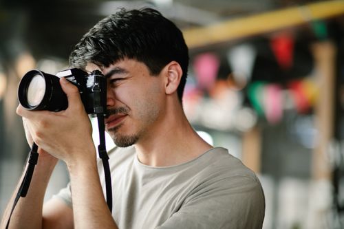 Free Focused photographer using a DSLR camera, capturing candid moments indoors. Stock Photo