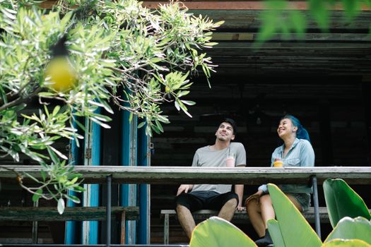 Two friends sitting together outdoors enjoying refreshing drinks and laughter.
