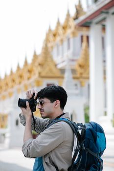 Man with camera taking photos of temple architecture, showcasing travel and exploration.