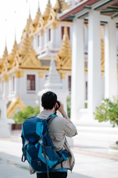 Photographer taking pictures of a traditional pagoda with a blue backpack.