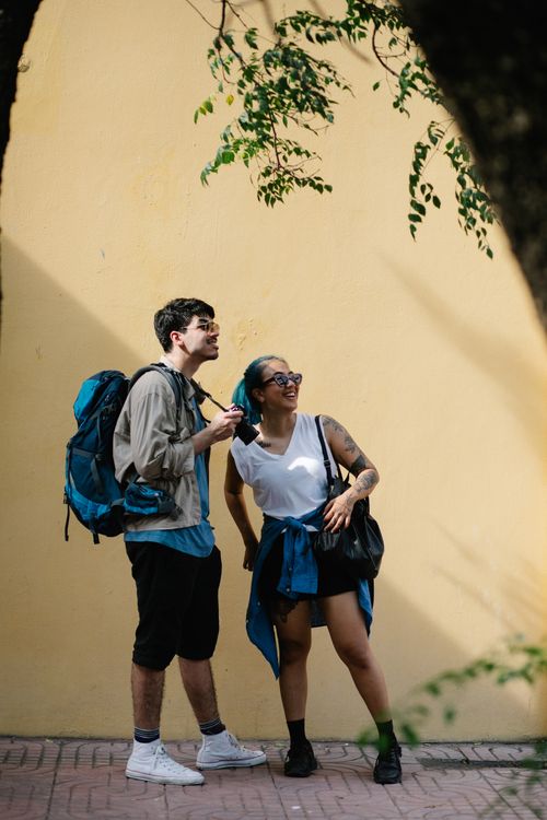 Free Two young adults stand near a yellow wall, enjoying an urban exploration adventure. Stock Photo