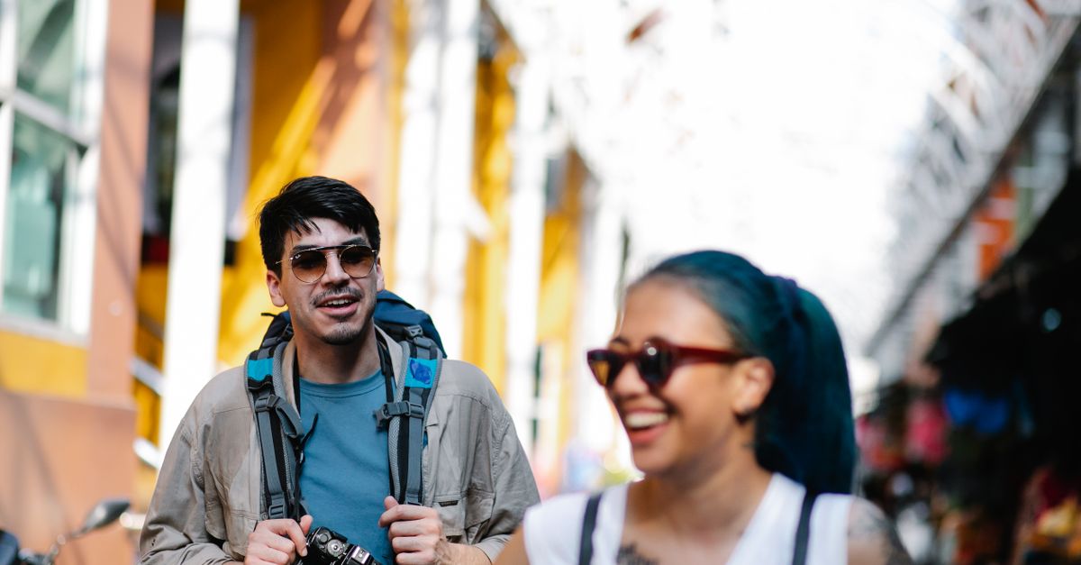 A candid shot of a traveler laughing with locals at a crowded market, looking confused but happy