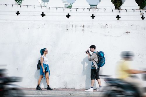 Free Photographer takes a candid shot of a young woman against a textured wall with blurred motorcycles passing. Stock Photo