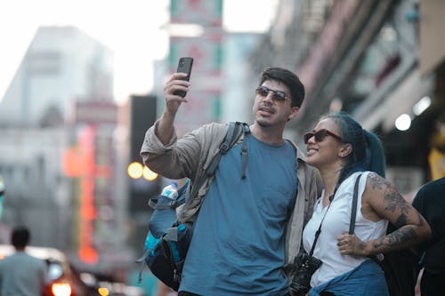 A Man beside a Woman Taking Photos Using a Smartphone