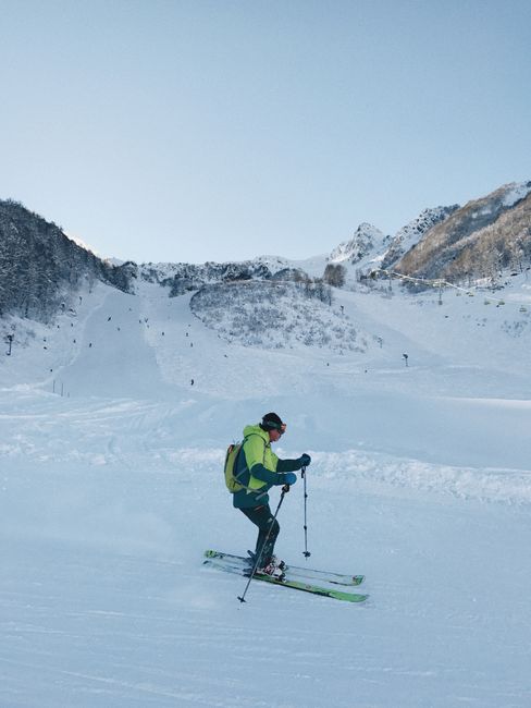 A skier traverses snow-covered slopes in Sochi, Russia, under a clear winter sky.