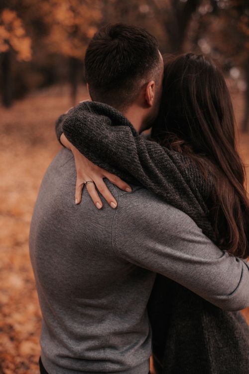 Free A couple lovingly embrace in a cozy autumn setting surrounded by orange leaves. Stock Photo